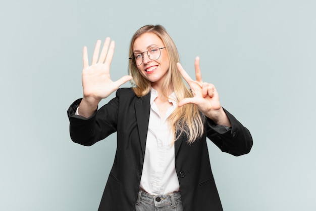 Jeune jolie femme d'affaires souriante et semblant amicale, montrant le numéro huit ou huitième avec la main vers l'avant, compte à rebours