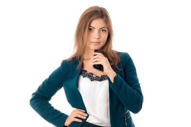 Jeune jolie femme d'affaires avec téléphone portable à la main en veste bleue en regardant la caméra isolée sur fond blanc