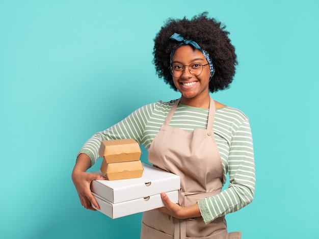 Jeune jolie femme afro livrer avec des boîtes de pizza et hamburgers à emporter