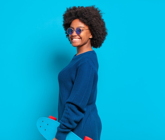 Jeune jolie femme afro avec une planche à roulettes