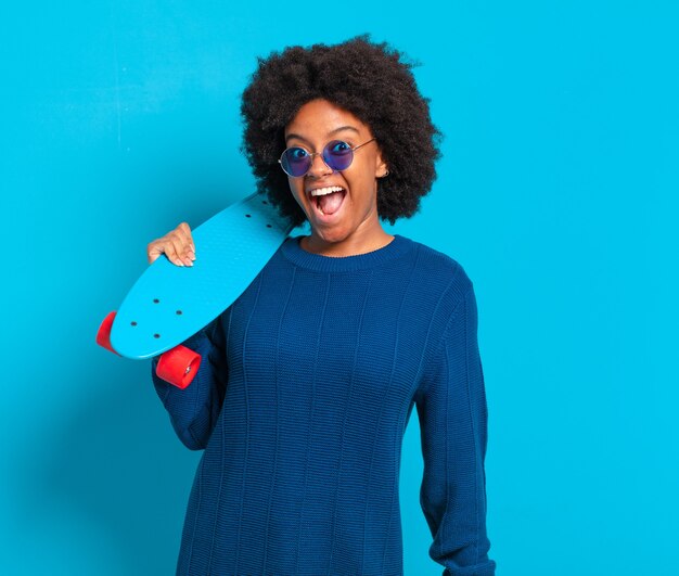 Jeune jolie femme afro avec une planche à roulettes