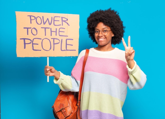 Jeune jolie femme afro protestant avec une bannière de pouvoir au peuple