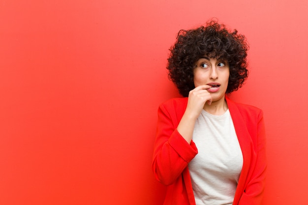 Jeune jolie femme afro avec un regard surpris, nerveux, inquiet ou effrayé, regardant de côté vers la surface