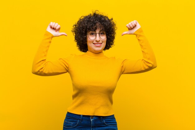 Jeune jolie femme afro se sentant fière, arrogante et confiante, à la recherche de satisfaction et de succès, pointant vers soi