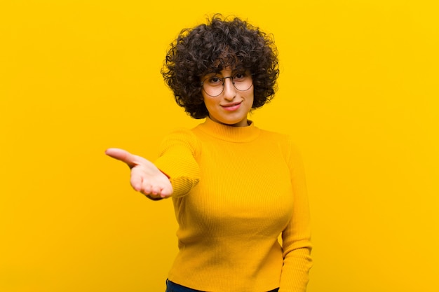 Photo jeune jolie femme afro souriante, heureuse, confiante et sympathique, offrant une poignée de main pour conclure un accord, coopérant