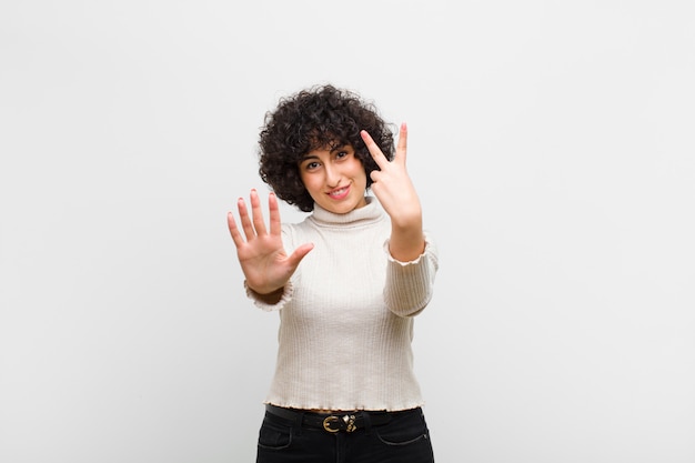 Jeune jolie femme afro souriante et sympathique, montrant le numéro sept ou septième avec la main vers l'avant, compte à rebours