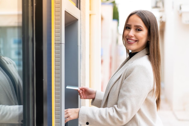 Jeune jolie femme à l'aide d'un guichet automatique