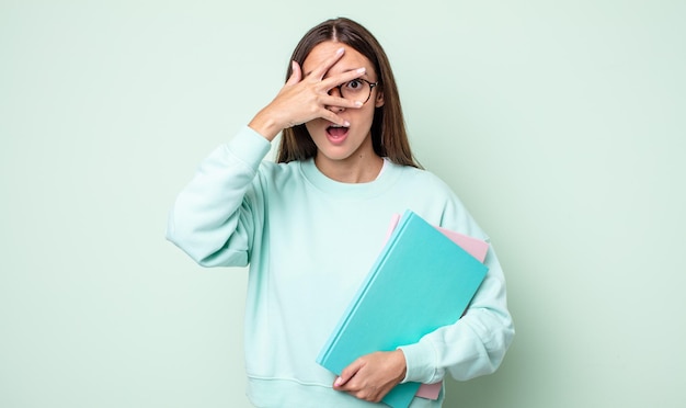 Jeune jolie femme à l'air choquée, effrayée ou terrifiée, couvrant le visage avec la main. étudiant universitaire