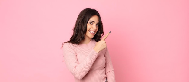 Jeune jolie femme à l'air excitée et surprise pointant vers le côté et vers le haut pour copier l'espace