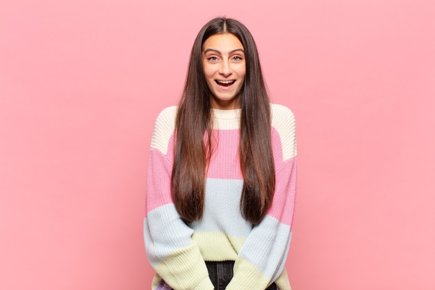 Jeune jolie femme à l'air heureuse et agréablement surprise, excitée par une expression fascinée et choquée