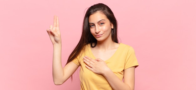 Jeune jolie femme à l'air heureuse, confiante et digne de confiance, souriante et montrant le signe de la victoire, avec une attitude positive