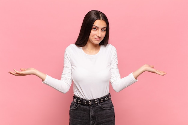 Jeune jolie femme à l'air perplexe, confuse et stressée, se demandant entre différentes options, se sentant incertaine