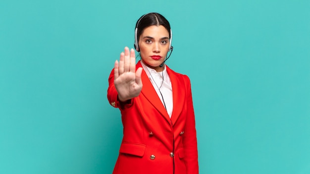 Jeune Jolie Femme à L'air Sérieuse, Sévère, Mécontente Et En Colère Montrant La Paume Ouverte Faisant Un Geste D'arrêt. Concept De Télévendeur