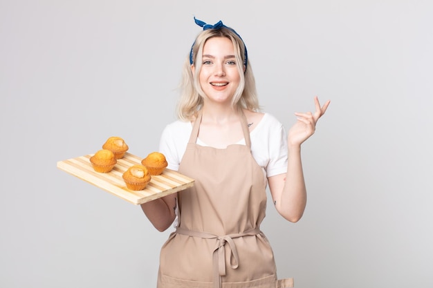 Jeune jolie femme albinos se sentant heureuse, surprise de réaliser une solution ou une idée avec un plateau à muffins