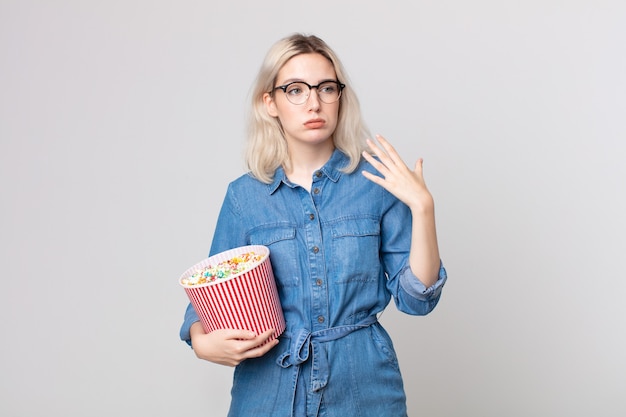 Jeune jolie femme albinos se sentant stressée, anxieuse, fatiguée et frustrée par un seau de pop corns