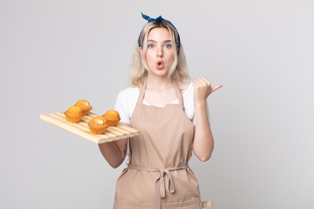 Jeune jolie femme albinos semblant étonnée d'incrédulité avec un plateau de muffins