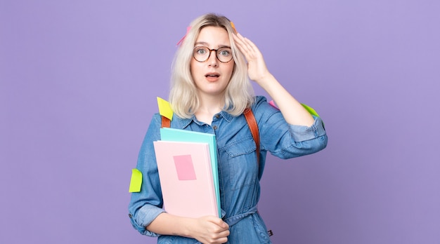 Jeune jolie femme albinos semblant heureuse, étonnée et surprise. concept d'étudiant