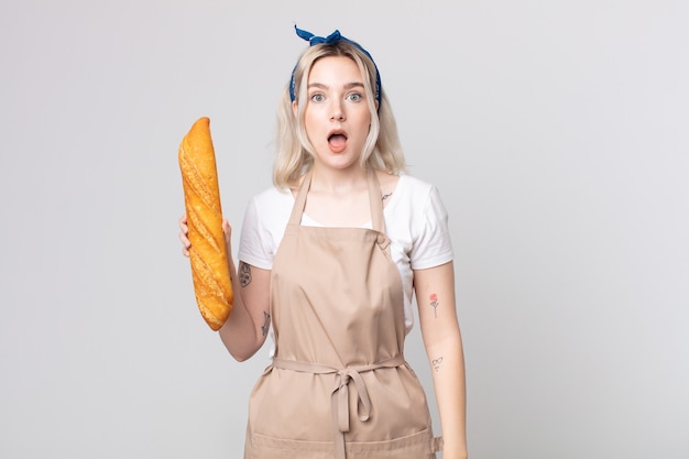 Jeune jolie femme albinos semblant très choquée ou surprise avec une baguette de pain