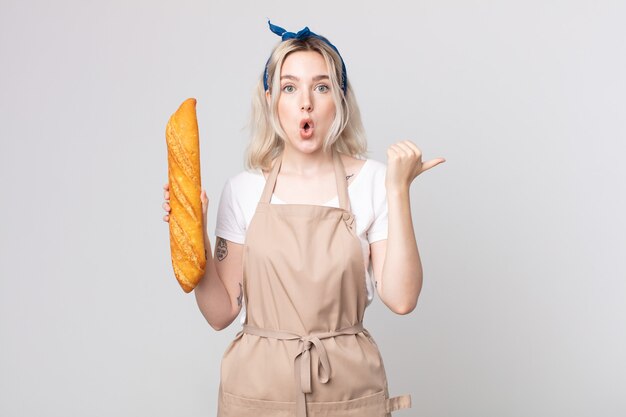 Jeune jolie femme albinos à la stupéfaction d'incrédulité avec une baguette de pain