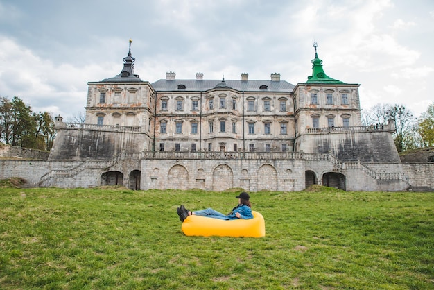 Jeune jolie femme allongée sur un matelas gonflable jaune devant le vieux château