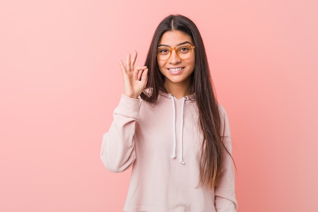 Jeune jolie femme arabe portant un look sport décontracté gai et confiant montrant un geste correct.