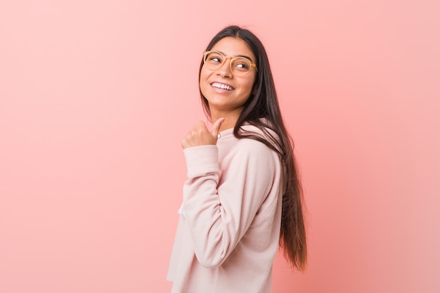 Jeune jolie femme arabe portant un look sport décontracté avec le pouce écarté, riant et insouciant.