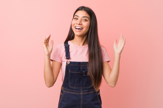 Jeune jolie femme arabe vêtue d&#39;un salopette en jeans célébrant une victoire ou un succès