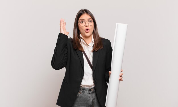 Jeune jolie femme architecte criant les mains en l'air, se sentant furieuse, frustrée, stressée et contrariée