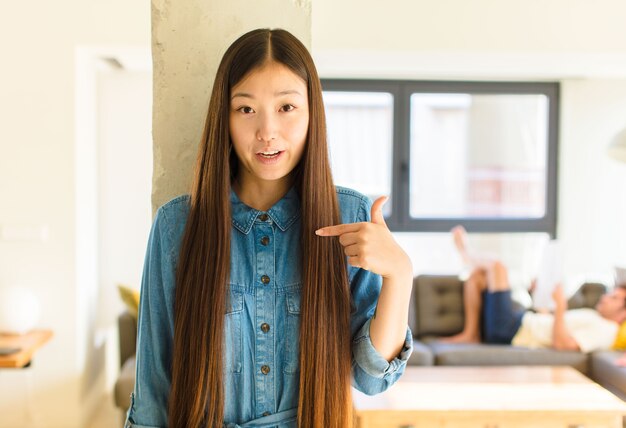 Jeune jolie femme asiatique à choqué et surpris avec la bouche grande ouverte, pointant vers soi