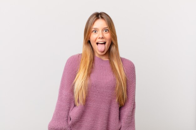 Jeune jolie femme avec une attitude joyeuse et rebelle, plaisantant et tirant la langue