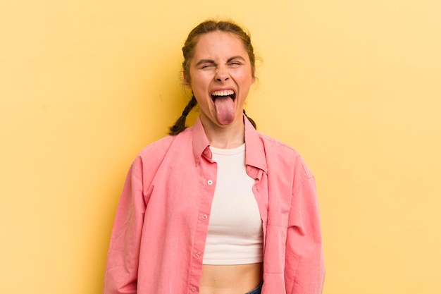 Jeune jolie femme avec une attitude rebelle insouciante joyeuse plaisantant et tirant la langue en s'amusant