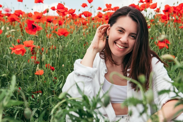 Jeune jolie femme au champ de fleurs de pavot