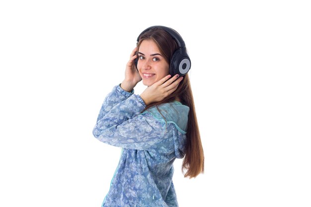 Jeune jolie femme aux cheveux longs en chemise écoutant de la musique dans des écouteurs avec les yeux fermés