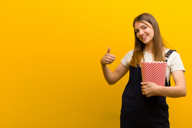 Jeune jolie femme aux pop corn sur orange