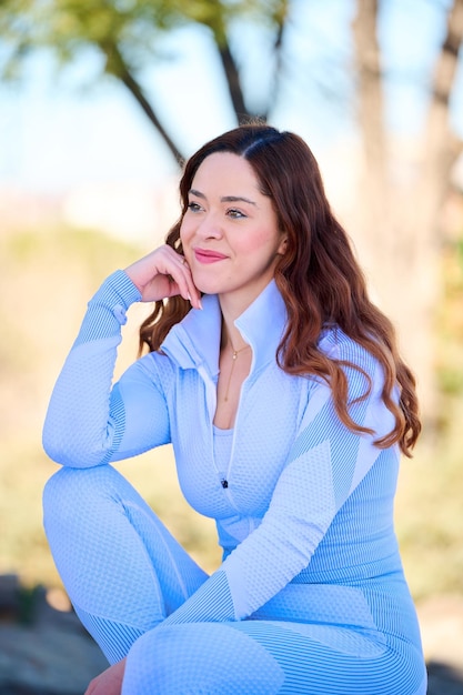 Jeune jolie femme aux yeux verts en robe bleue assise dans le parc de la ville