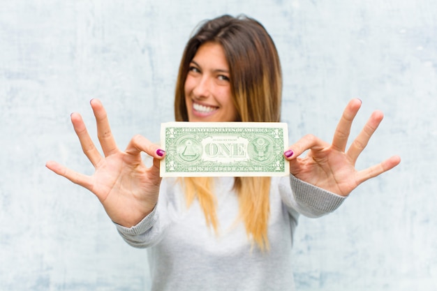 Photo jeune jolie femme avec des billets contre le mur de grunge