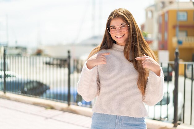 Une jeune et jolie femme blanche avec des lunettes à l'extérieur avec une expression faciale de surprise