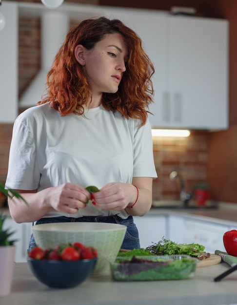 Jeune jolie femme blogueuse tourne une vidéo d'une recette de salade sur un appareil photo de smartphone