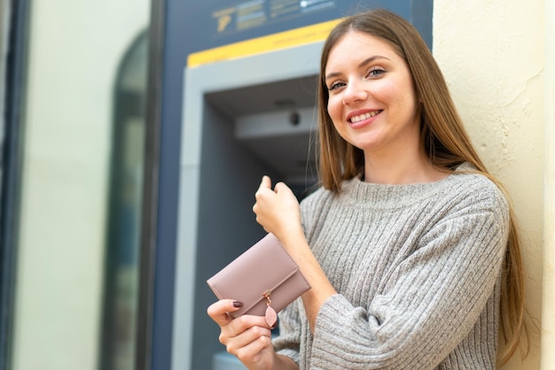 Jeune jolie femme blonde à l'aide d'un guichet automatique