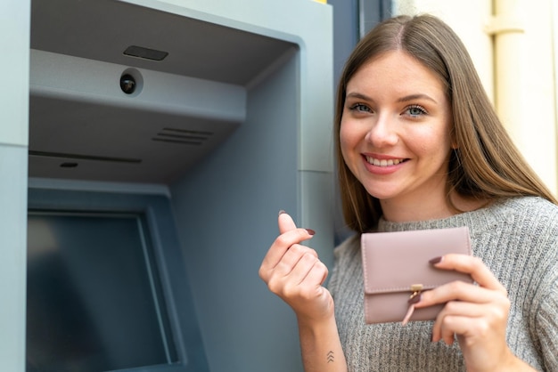 Jeune jolie femme blonde à l'aide d'un guichet automatique