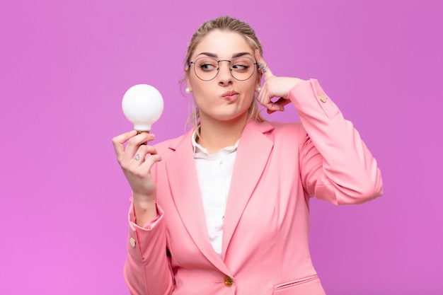 Jeune jolie femme blonde ayant une idée avec une ampoule