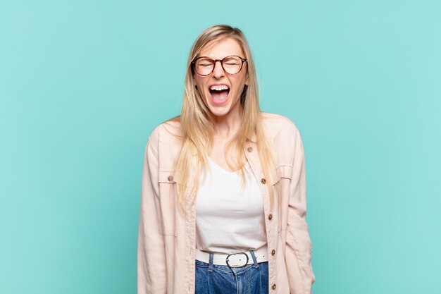 Jeune jolie femme blonde criant agressivement, ayant l'air très en colère, frustrée, indignée ou agacée, criant non