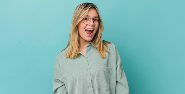 Jeune jolie femme blonde avec un grand sourire amical et insouciant à la détente positive et heureuse