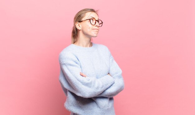 Jeune jolie femme blonde haussant les épaules, se sentant confuse et incertaine, doutant les bras croisés et le regard perplexe