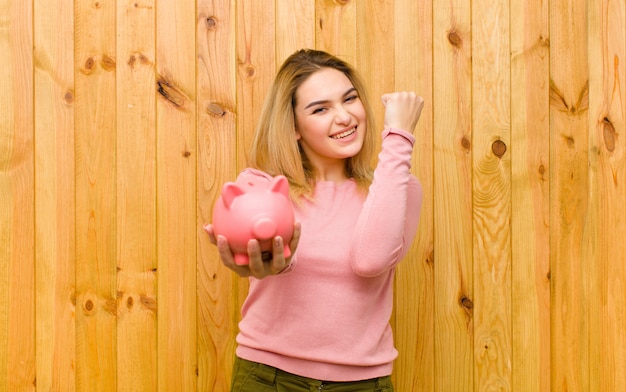 Jeune jolie femme blonde avec un mur de bois tirelire