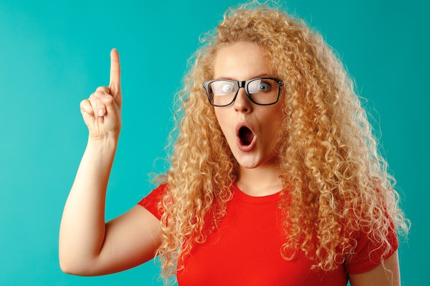 Jeune jolie femme blonde pointant son doigt pour copier l'espace