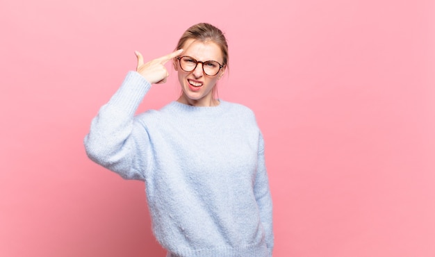 Jeune jolie femme blonde se sentant confuse et perplexe, montrant que vous êtes fou, fou ou fou