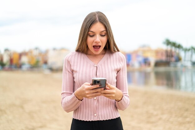 Jeune jolie femme blonde surprise et envoyant un message