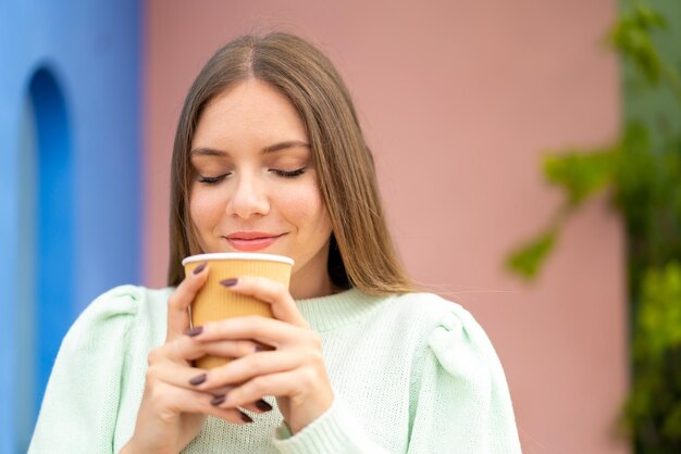 Jeune jolie femme blonde tenant un café à emporter