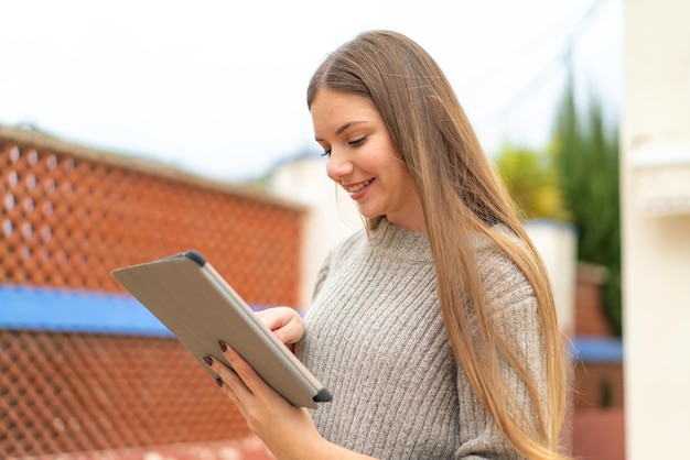 Jeune jolie femme blonde touchant l'écran de la tablette avec une expression heureuse